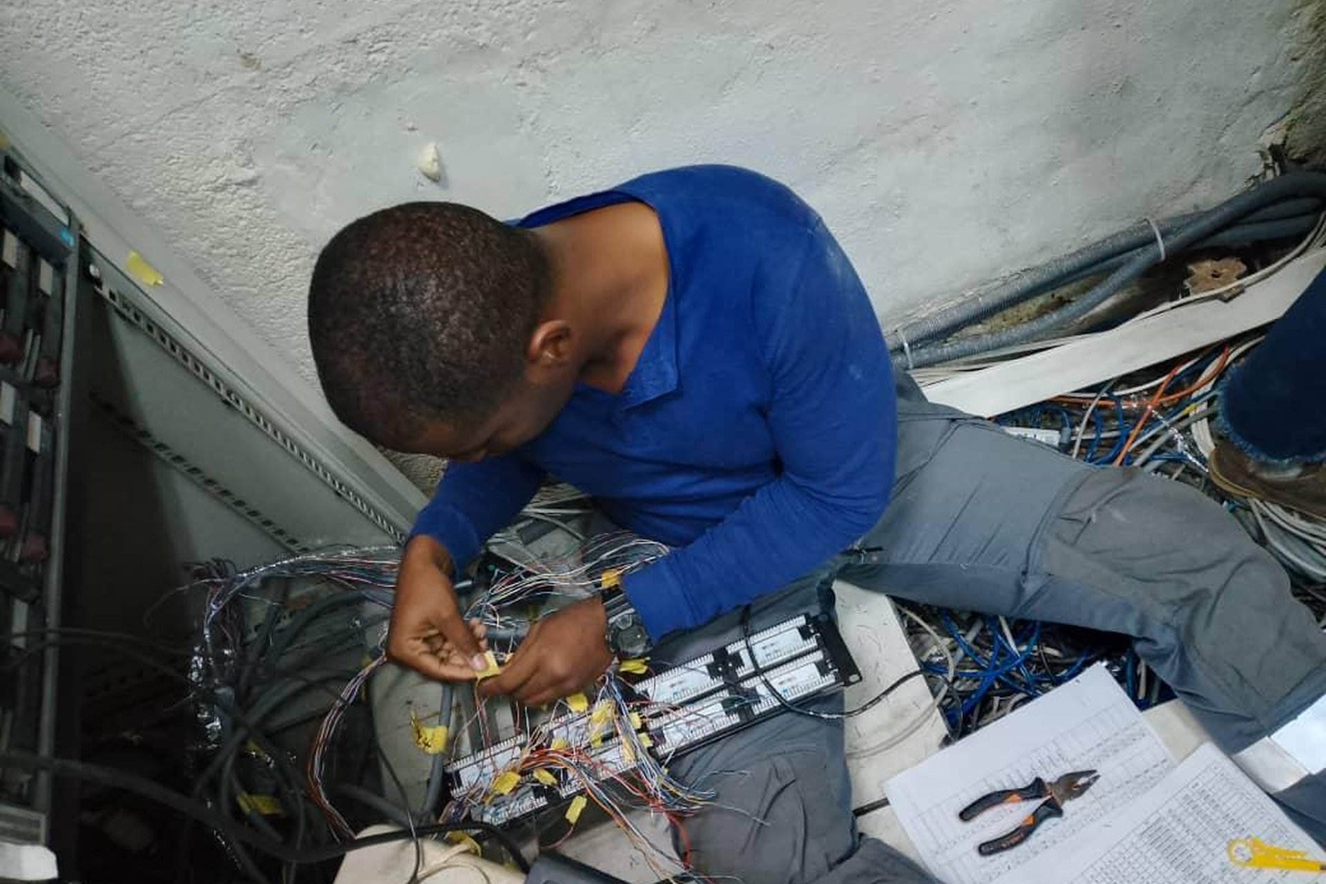 Technicien Connect Office réalisant le câblage d'une baie réseau